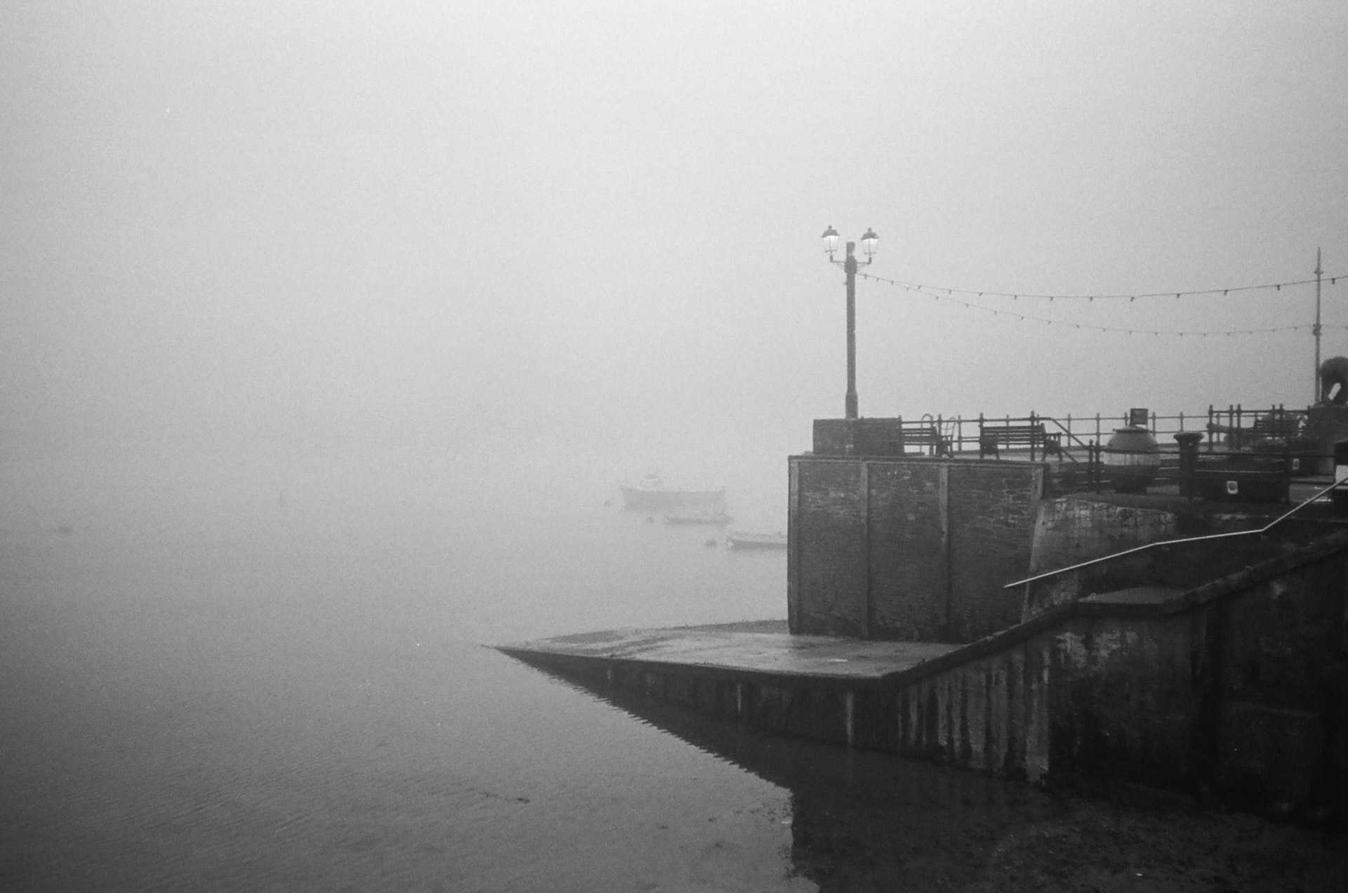 A black and white photograph of Fowey Harbour streetlights on a misty morning taken on Ilford HP5 Plus film stock.