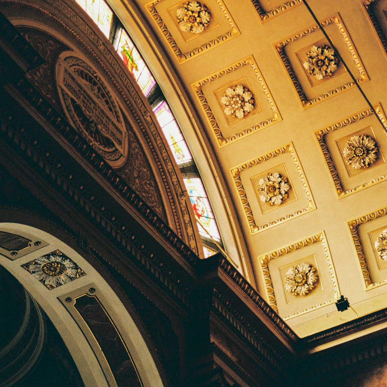 Stained glass windows with light pouring through onto gold gilded ceiling in a church in Lecco, Italy, taken on Kodak Gold 200 film stock.