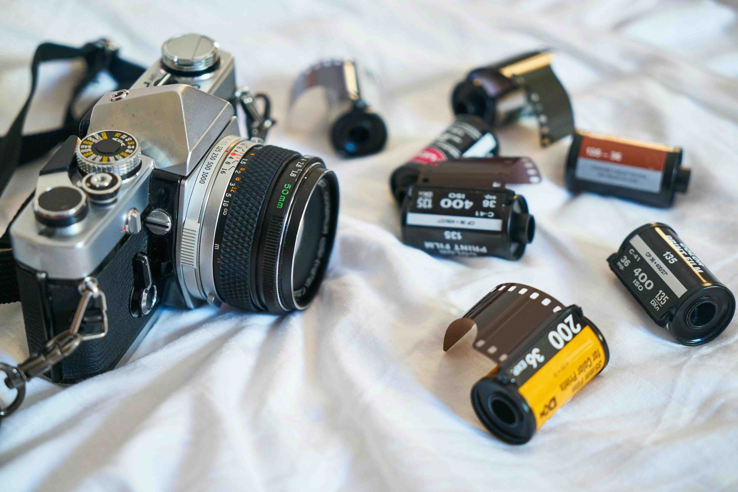 A film camera lying next to various rolls of different film stock